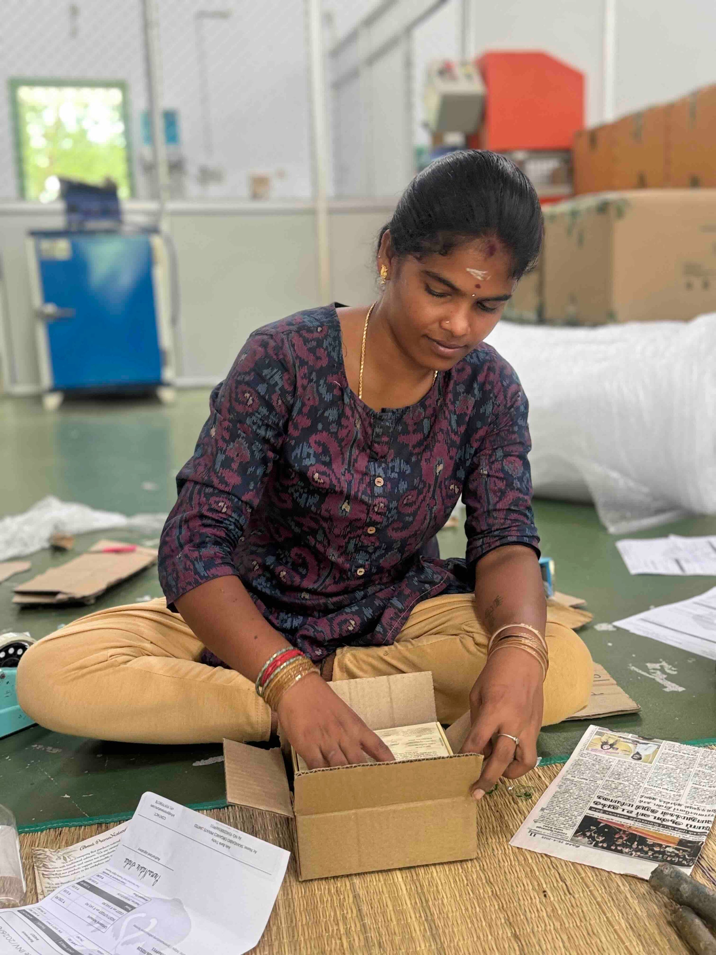 A woman packing a PremaNature order into a cardboard carton by hand