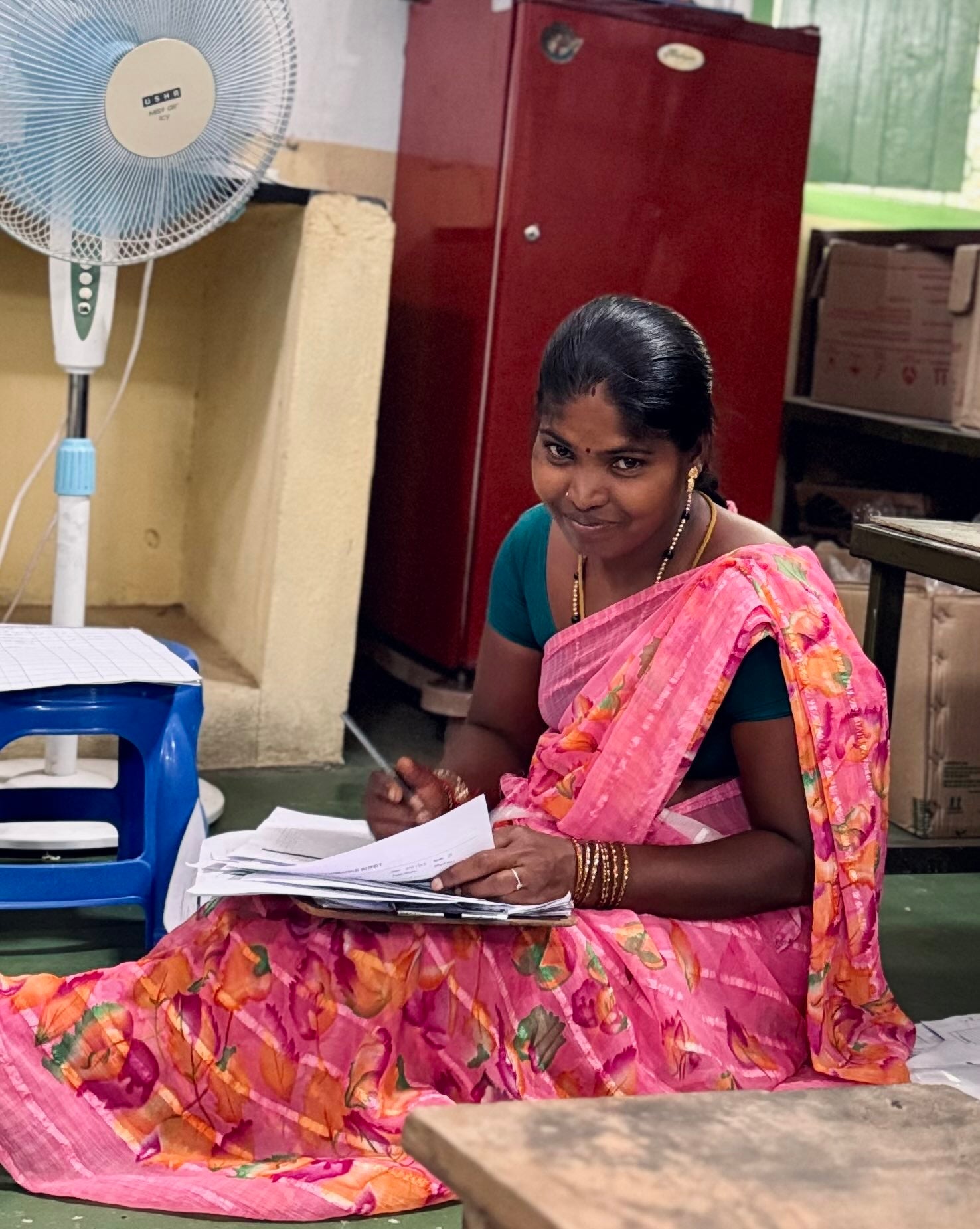 A woman of the PremaNature team smiling as she works through order paperwork on the workshop floor